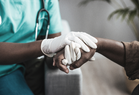 A nurse holding a patients hands.