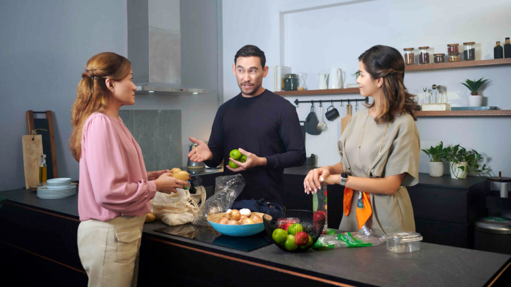 Three people preparing food in a kitchen.