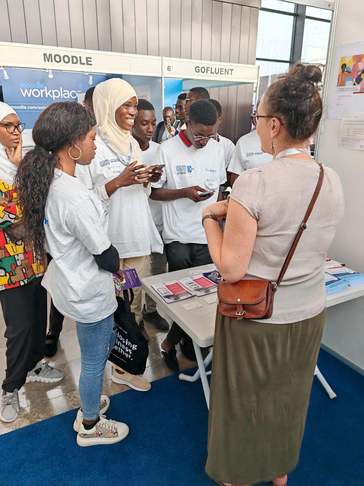 A group of people standing next to a workshop stand at a conference.