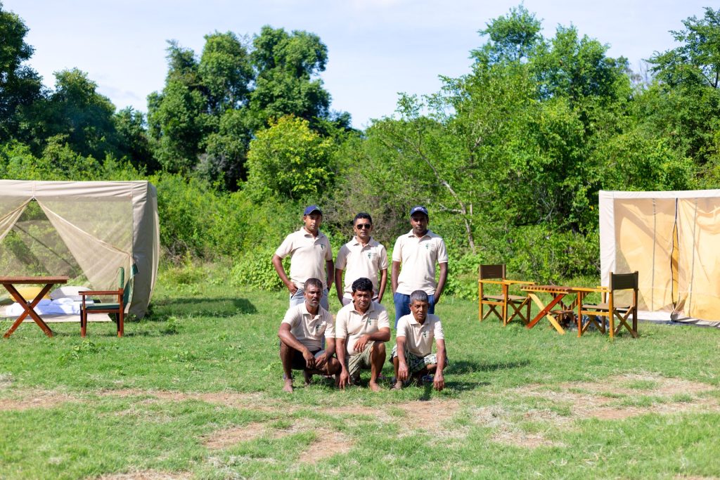 A group of male guides posing for a photo near a campsite.