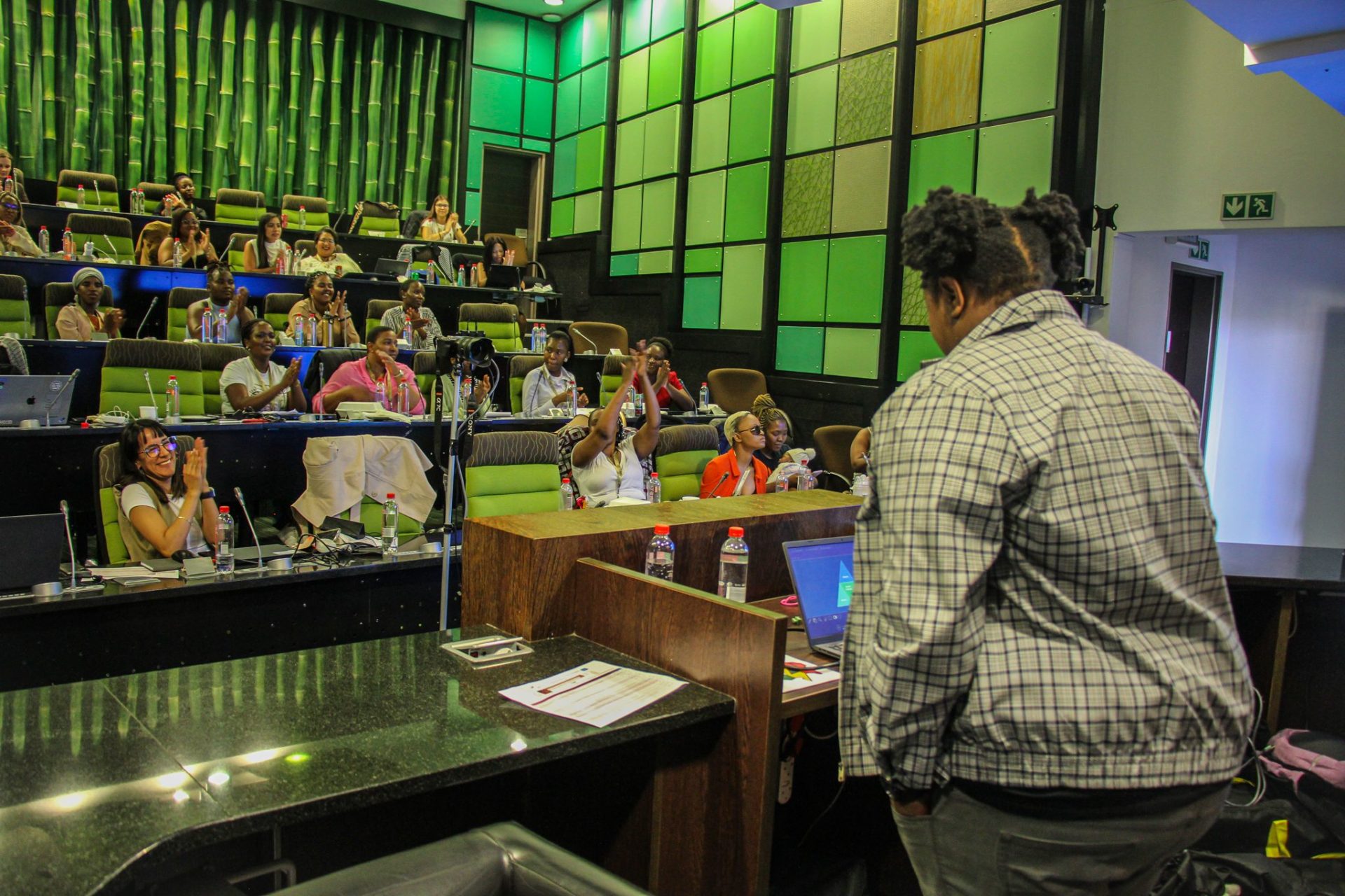 Auditorium with female participants applaiding a female speaker