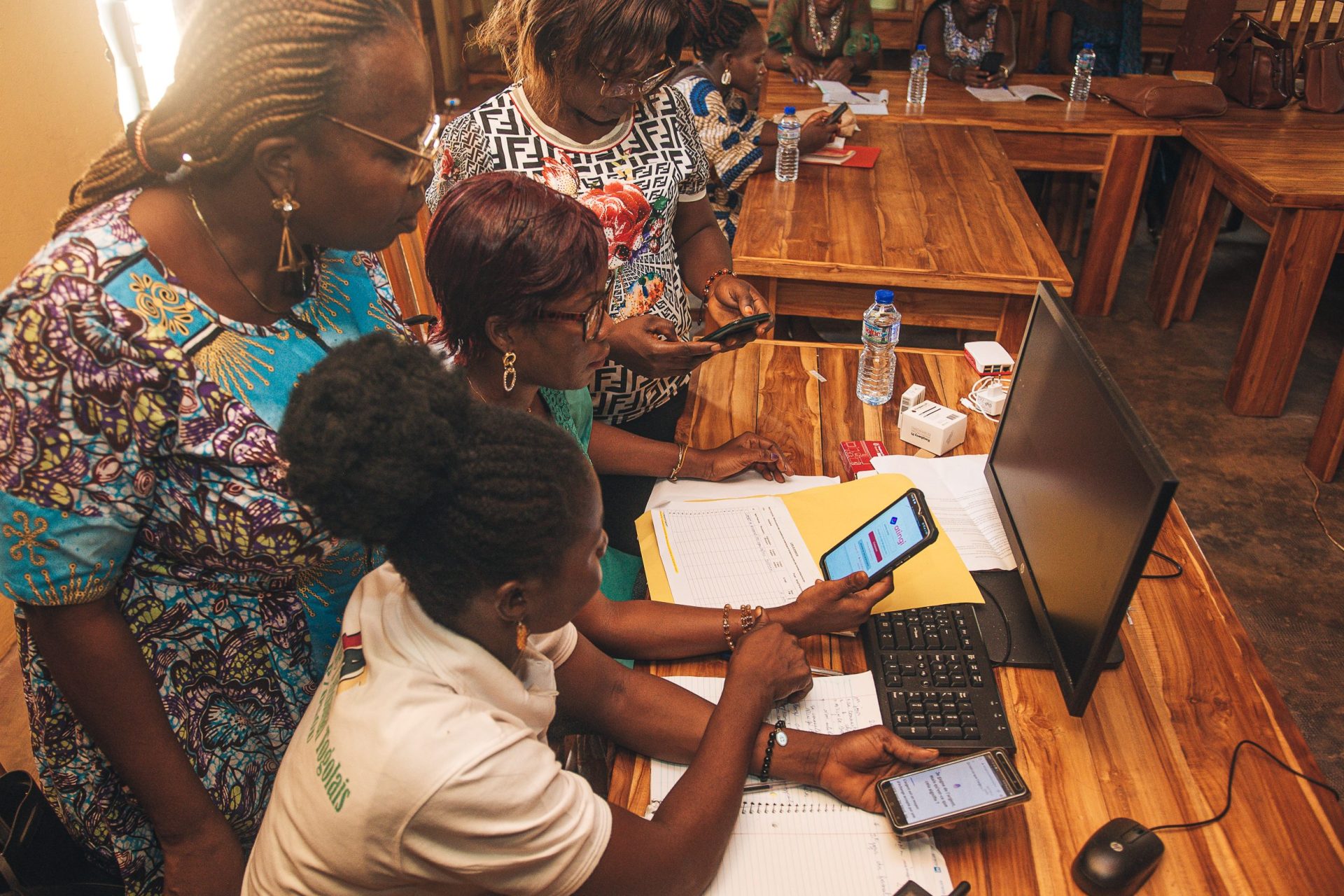 Women helping eachother registering on atingi on a mobile device