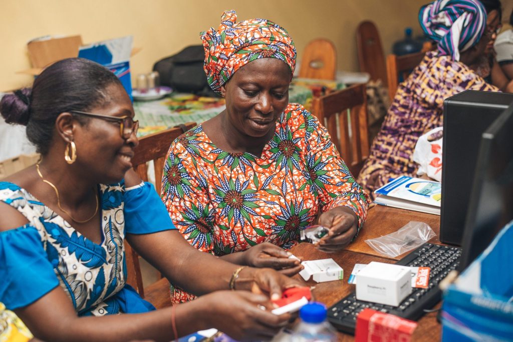 Two women assembling a computer device.