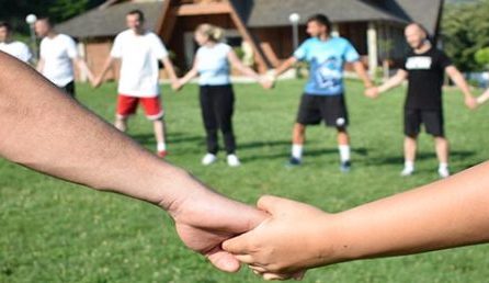 People on a lawn holding hands in a circle