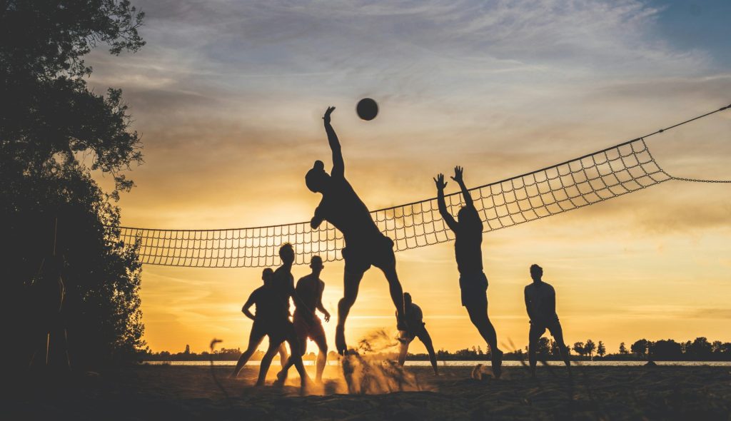 People playing beach volleyball at sunset